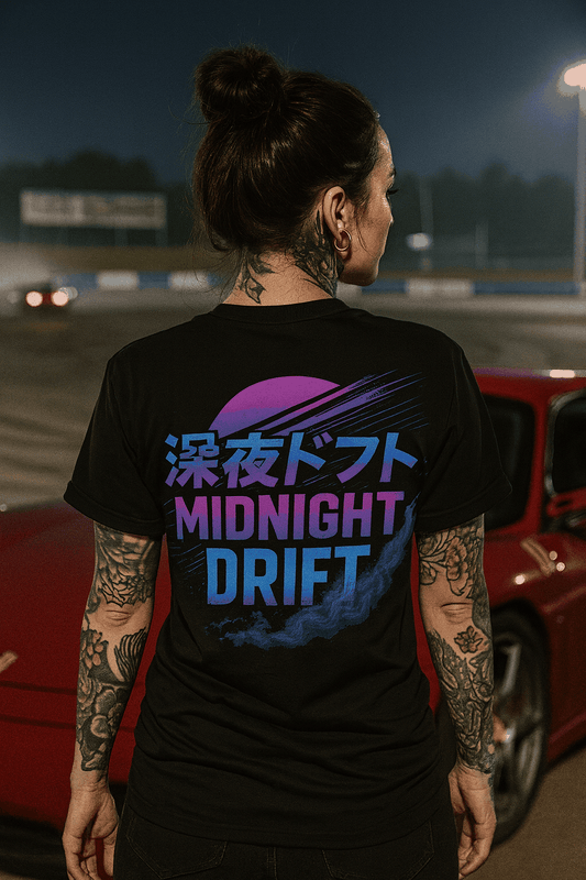 Person wearing black oversized Midnight Drift oversized tee with vibrant neon JDM street style graphic on back at night near a red car.