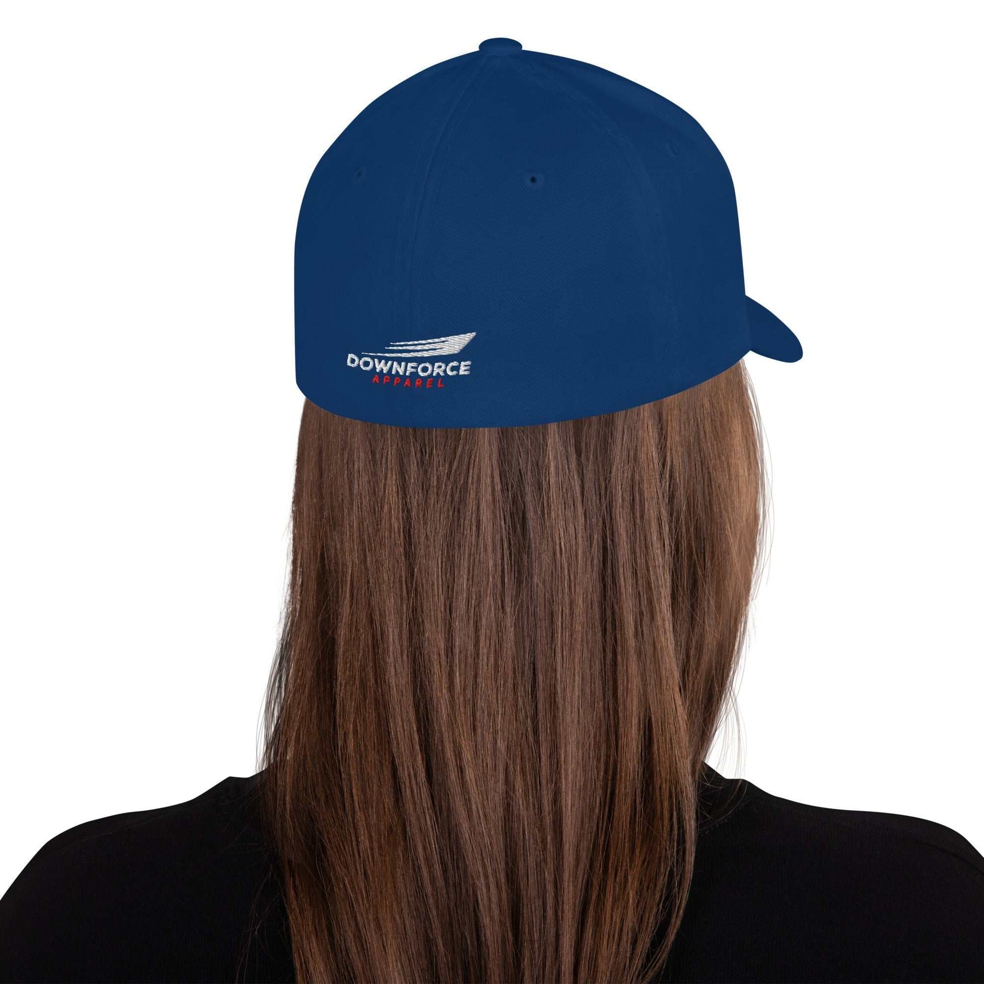 Back view of blue Downforce Apparel Flexfit cap with embroidered logo on a person with long brown hair