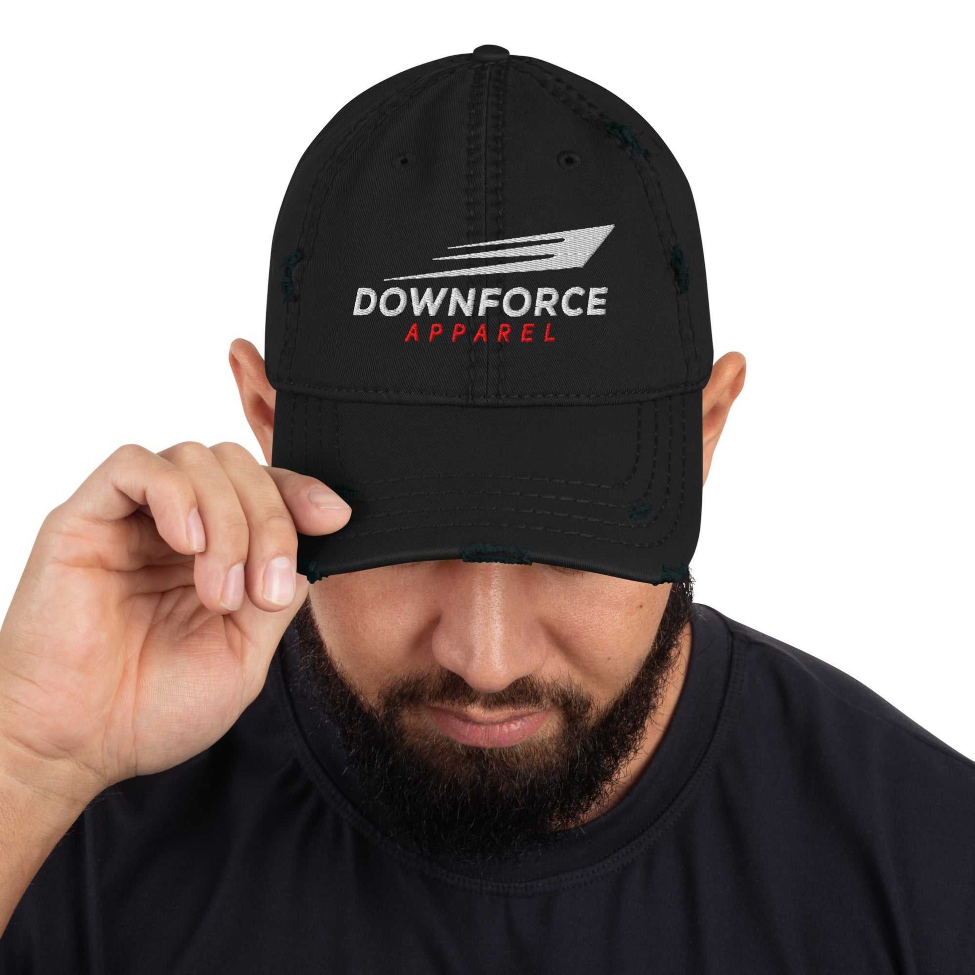 Black DownForce Apparel distressed dad hat with logo embroidery worn by man adjusting brim