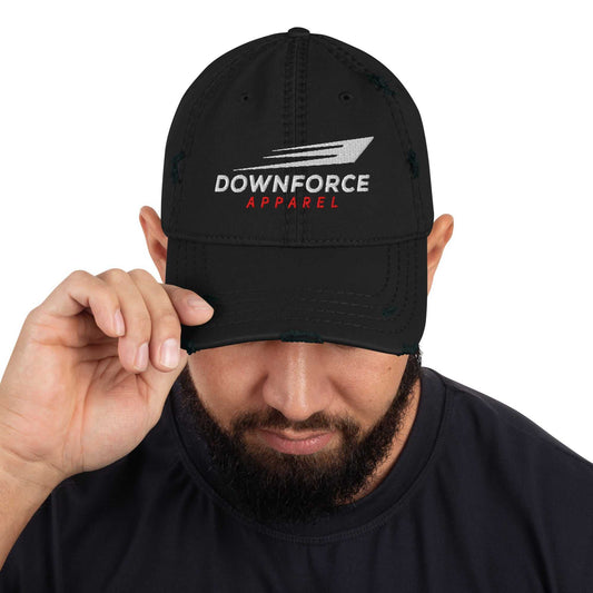 Black DownForce Apparel distressed dad hat with logo embroidery worn by man adjusting brim