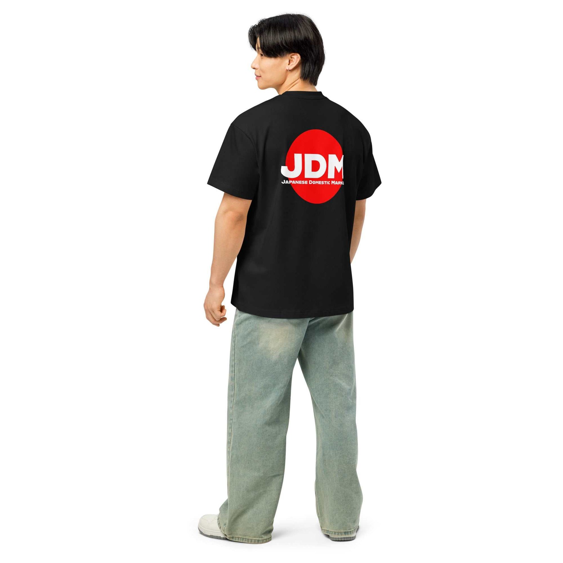 Man wearing black JDM box tee with red and white Japanese Domestic Market logo on back, paired with light blue jeans and white shoes.